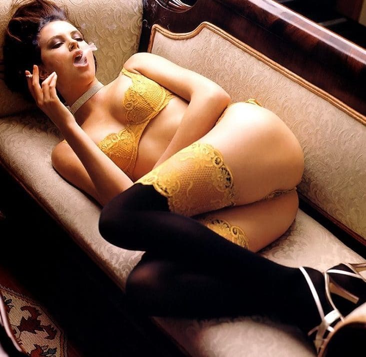 Charlize Theron smoking on a couch in yellow lingerie