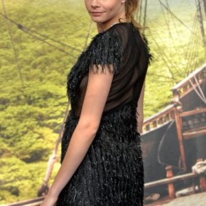 Cara Delevingne at Pan premiere in London in black short dress looking back at the camera