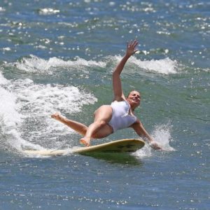 Margot Robbie in the ocean falling off of a surf board