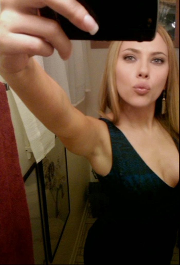 Scarlett Johansson taking a selfie in front of a mirror and making a kissy face