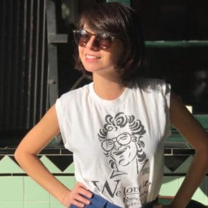 Kate Micucci in a white muscle tank and sunglasses
