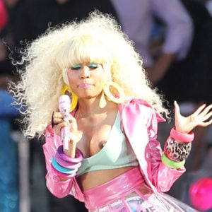 Nicki Minaj singing on stage with blond hair as nipple slips out of top