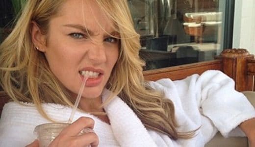 Candice Swanepoel in a robe biting on a straw