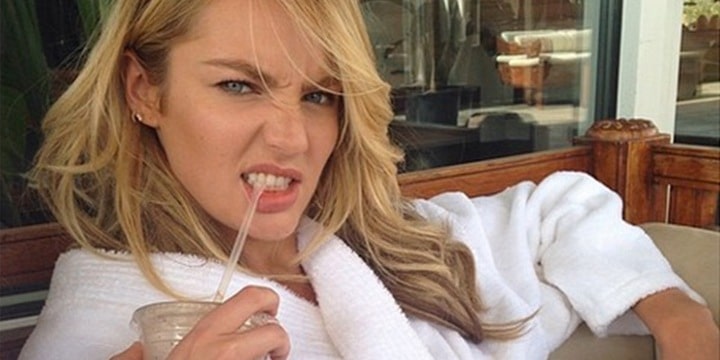 Candice Swanepoel in a robe biting on a straw