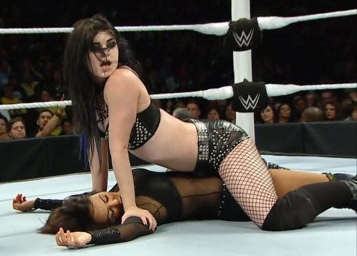 Paige (WWE) pinning a girl down in the ring an she sticks her ass out
