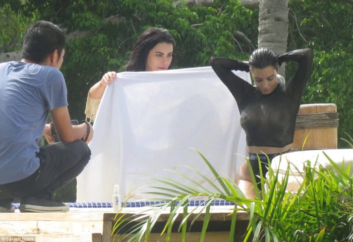 Kim Kardashian in see through black top sitting down