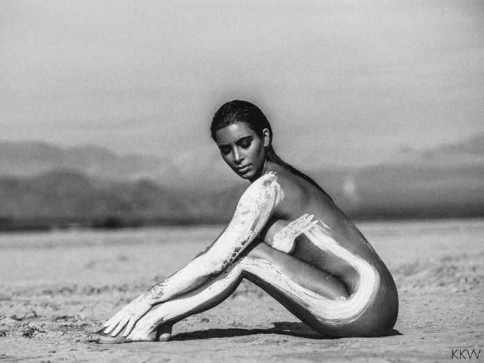 Kim Kardashian sitting down in the desert nude